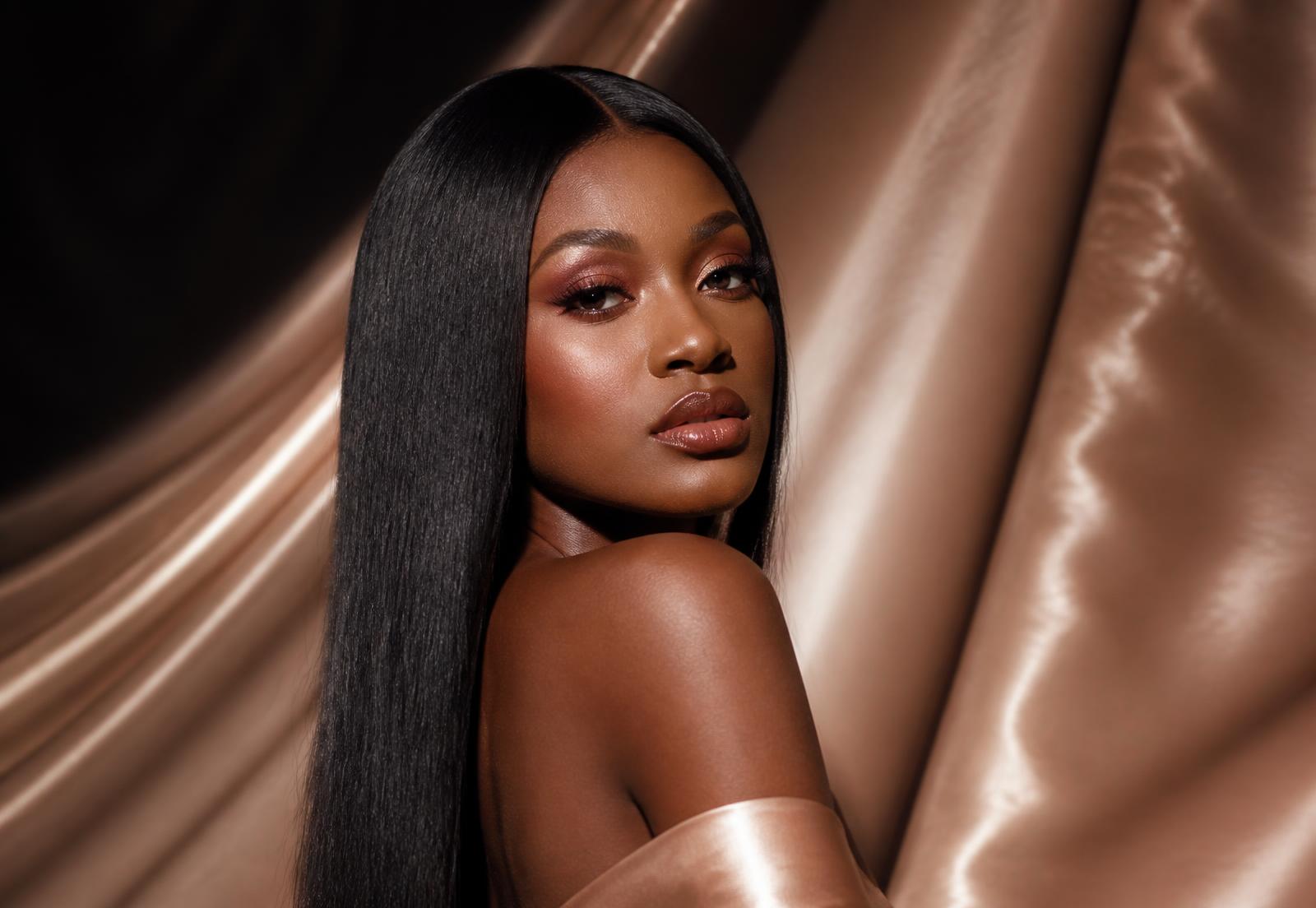 Model wearing a long, glossy human-hair unit against ivory silk